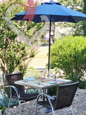 a table with a blue umbrella and two chairs at HOTEL RESTAURANT OLYMPE in Aix-en-Provence