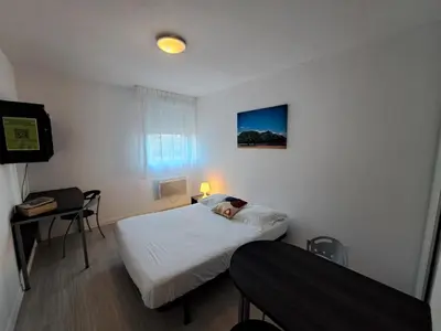 a small room with two beds and a table and a desk at Résidence Les Académies Aixoise in Aix-en-Provence