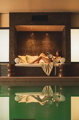 a woman sitting on a bed reading a book at Les Lodges Sainte-Victoire Hotel & Spa in Aix-en-Provence
