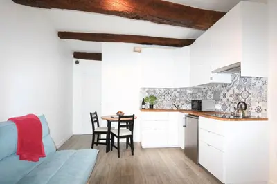 a kitchen and dining room with white cabinets and a table at ROGERIO en PLEIN CENTRE DE L'ISLE SUR SORGUE in LʼIsle-sur-la-Sorgue