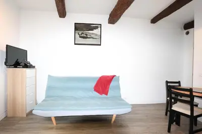 a living room with a blue couch with a red pillow at ROGERIO en PLEIN CENTRE DE L'ISLE SUR SORGUE in LʼIsle-sur-la-Sorgue