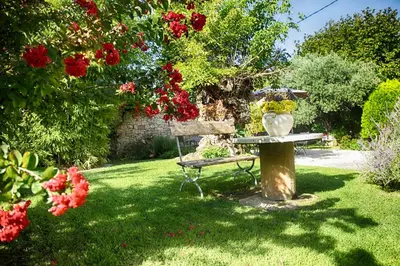 a garden with a table and a bench and flowers at Bastide Sainte Agnès in Carpentras