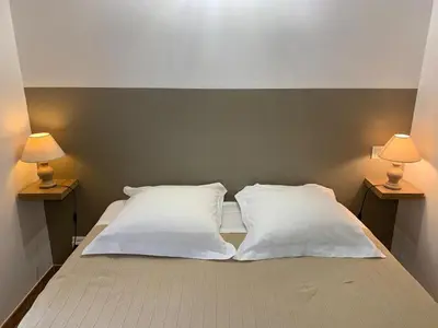 a bed with two white pillows and two lamps at Gîte L'Olivier (Bastide Sainte Agnès) in Carpentras
