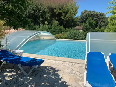 a swimming pool with two chairs and a swimming poolvisor at Gîte L'Olivier (Bastide Sainte Agnès) in Carpentras