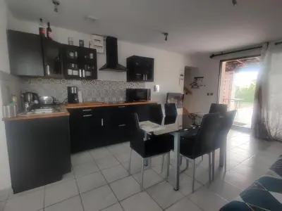 a kitchen with black cabinets and a table and chairs at Gîte du Charme Provençal in Sénas