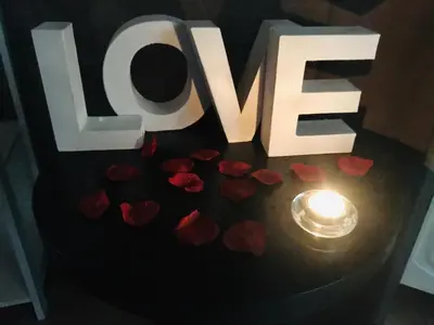 a table with a love sign and hearts and a candle at Une Pause Douceur - Suite Orchidée in Eyguières