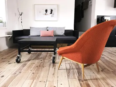 a living room with a black couch and orange chairs at La Magnanerie in LʼIsle-sur-la-Sorgue