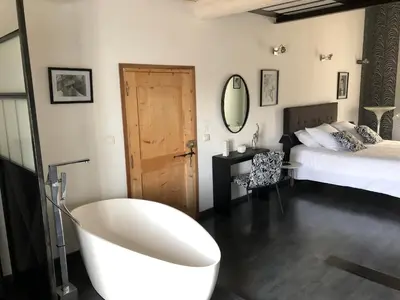 a bathroom with a bath tub and a bed at B&B dans Mas en pierres in Robion en Luberon