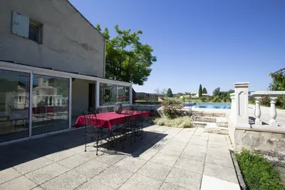 a patio with a red table and chairs next to a building at Villa charmante à La Tour-d'Aigues avec piscine privée in La Tour-dʼAigues