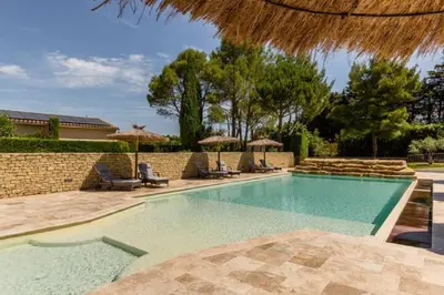 a swimming pool with chairs and umbrellas at La Bastide de l Etang in LʼIsle-sur-la-Sorgue
