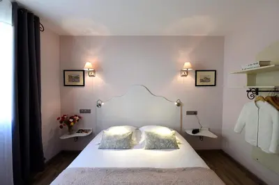 a bedroom with a white bed with two pillows at The Originals Boutique, Hôtel du Parc, Cavaillon in Cavaillon