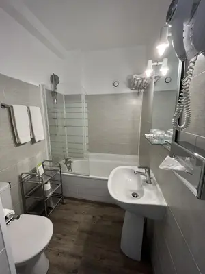 a bathroom with a sink and a tub and a toilet at The Originals Boutique, Hôtel du Parc, Cavaillon in Cavaillon