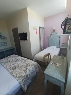 a hotel room with two beds and a table at The Originals Boutique, Hôtel du Parc, Cavaillon in Cavaillon