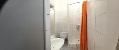 a bathroom with an orange shower curtain and a toilet at Hôtel Du Cours in Pertuis