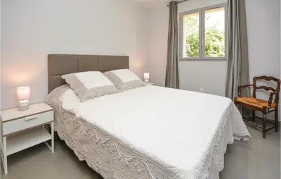 a bedroom with a white bed with a chair and a window at Awesome Home In Saint-Rémy-De-Provence in Saint-Rémy-de-Provence