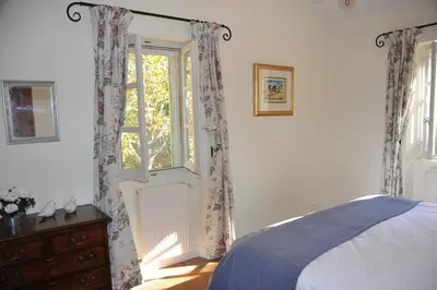 a bedroom with a bed and a window with curtains at Mas de Michel in Bonnieux