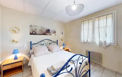 a bedroom with a blue and white bed and two windows at 2 Bedroom Gorgeous Apartment In Caromb in Caromb
