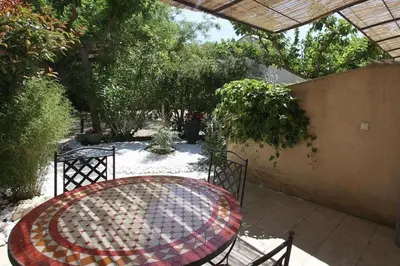 a patio with a table and chairs and trees at CLOS DE LA FONT in Mollégès