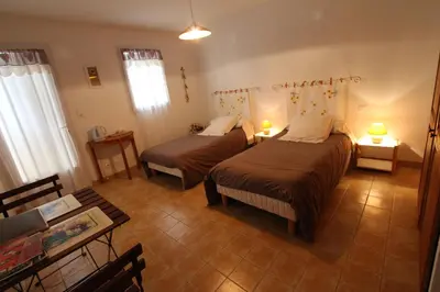 a bedroom with two beds and a living room with a table at CLOS DE LA FONT in Mollégès