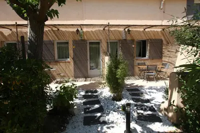 a courtyard with a house with a table and chairs at CLOS DE LA FONT in Mollégès