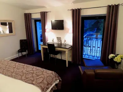 a hotel room with a desk and a bed and a window at Logis Hôtel Restaurant du Parc in Fontaine-de-Vaucluse