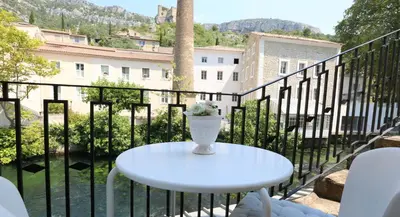 a white table with a vase on a balcony at Logis Hôtel Restaurant du Parc in Fontaine-de-Vaucluse