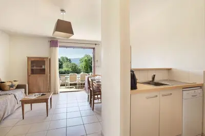 a kitchen and a living room with a table at Résidence Odalys Les Soleils du Luberon in Bonnieux