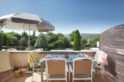 a table and chairs with an umbrella on a patio at Résidence Odalys Les Soleils du Luberon in Bonnieux