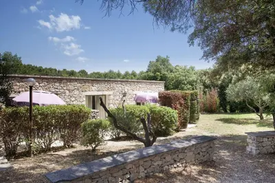 a stone house with a garden and a stone wall at Résidence Odalys La Bastide des Chênes in Gordes