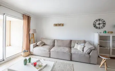 a living room with a couch and a clock on the wall at Le Cigalou in Mallemort