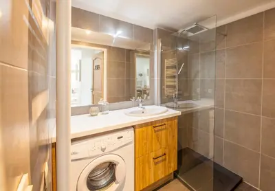 a bathroom with a washing machine and a sink at Le Cigalou in Mallemort