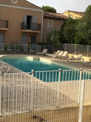 a swimming pool with a white fence next to a house at Le Cigalou in Mallemort