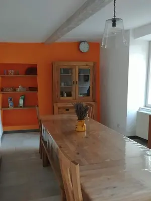 a dining room with a large wooden table and orange walls at Gîte Pilpoil in Sault-de-Vaucluse