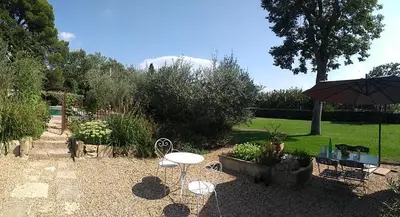 a garden with a table and chairs and an umbrella at Mas de Camejean in Lambesc