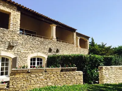 a stone house with a stone wall and flowers at Hostellerie Le Roy Soleil in Ménerbes