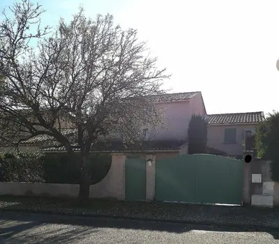 a fence with a tree in front of a house at Maison le Pastaga in Caromb