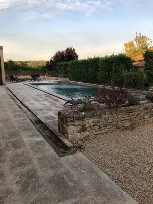 a swimming pool in a yard with a stone wall at Villa dans le LUBERON à 2 km de LOURMARIN in Lauris