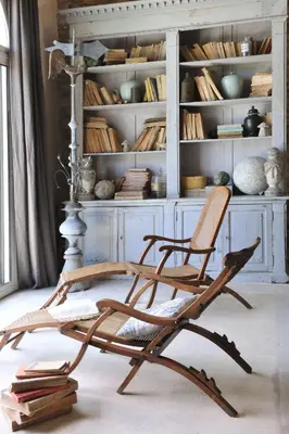 a wooden rocking chair in front of a book shelf at La Bastide de Marie, Maisons et Hôtels Sibuet in Ménerbes