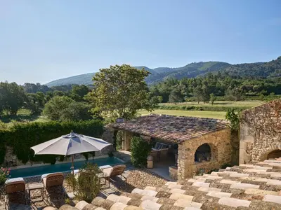 an outdoor patio with an umbrella and a pool at La Bastide de Marie, Maisons et Hôtels Sibuet in Ménerbes