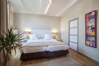 a white bedroom with a large bed and a table at Hôtel de France in Aix-en-Provence