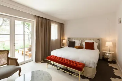 a bedroom with a large bed with a red bench at Mas des Herbes Blanches Hôtel & Spa – Relais & Châteaux in Joucas