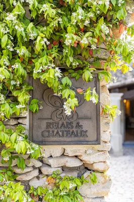 a sign on the side of a stone wall with flowers at Mas des Herbes Blanches Hôtel & Spa – Relais & Châteaux in Joucas