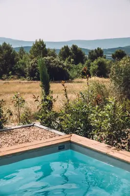 a swimming pool in a garden with a field in the background at Mas des Herbes Blanches Hôtel & Spa – Relais & Châteaux in Joucas