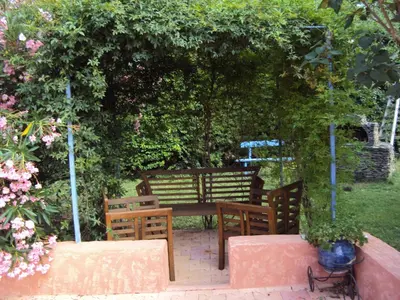 a wooden table and chairs under a hedge with flowers at Maison d'Hôtes La Douloire in Pernes-les-Fontaines