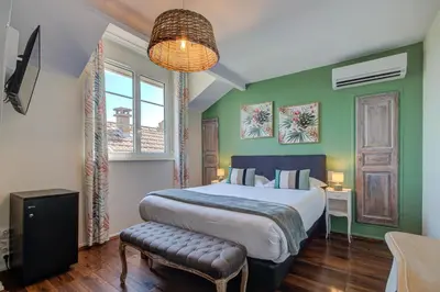 a bedroom with a large bed with green walls at Logis Hotel Le Blason de Provence in Monteux