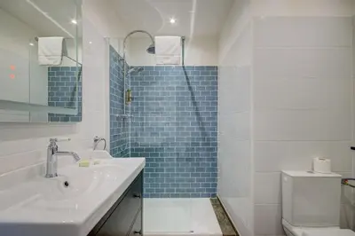 a bathroom with a sink and a toilet and blue tiles at Logis Hotel Le Blason de Provence in Monteux