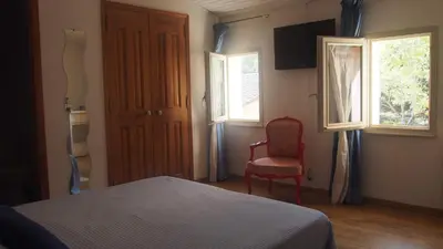 a bedroom with a bed and a chair and windows at Mas du Kairos in Venasque
