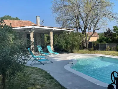 a swimming pool with two chairs next to a house at Villa Camille in Céreste