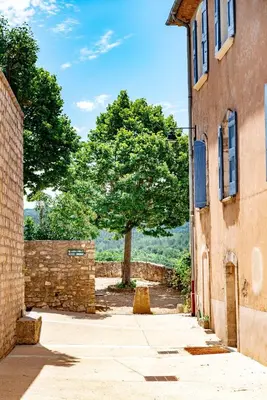an alley between two buildings with a tree in the background at Le Nesk Ventoux - Hotel in Sault-de-Vaucluse