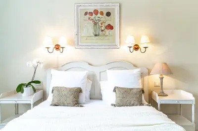 a bedroom with a white bed with white pillows at Hôtel Le Pré Saint Michel in Manosque